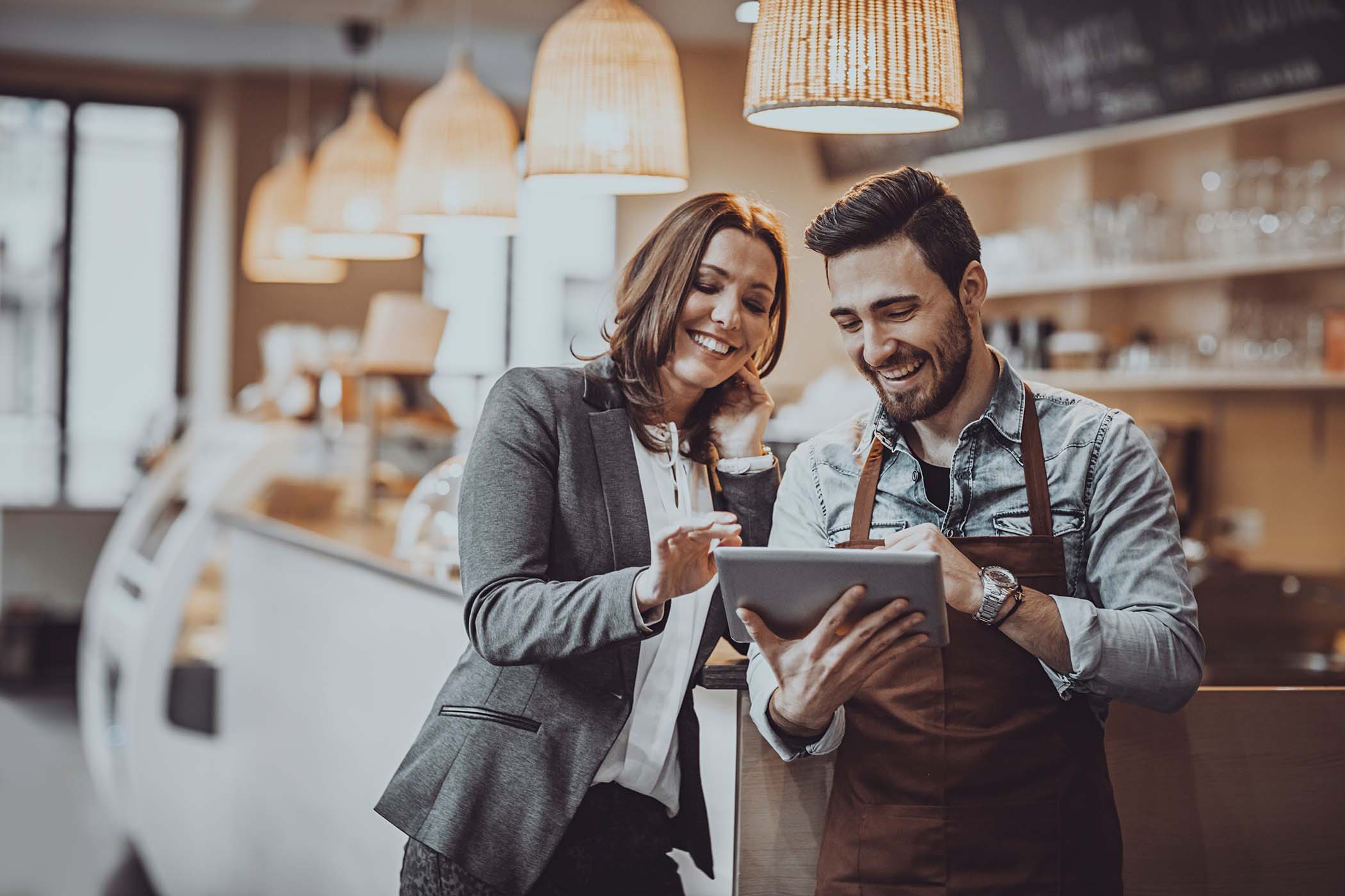 Checking website Shot of a smiling cafe owner and employee barista standing inside a coffee shop looking at new menu on a digital tablet Restaurant Stock Photo