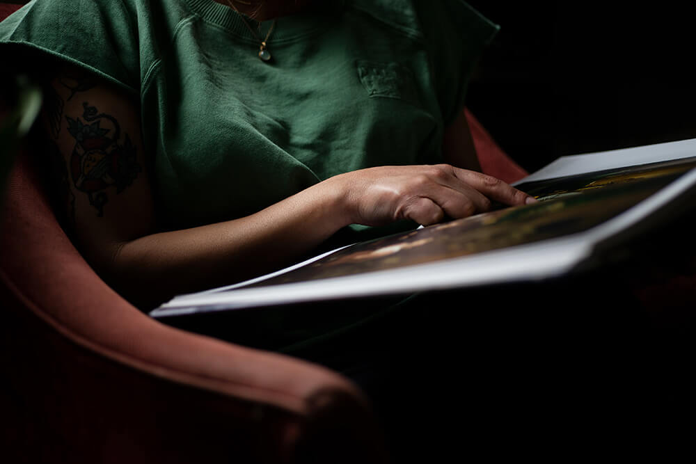 Torso of a person reading a large book in a red armchair