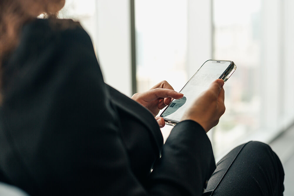 A woman looks at her smartphone and scans a social media page.